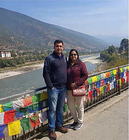 A couple beside prayer flags above the river at Punakha on an Ayansh Holidays trip