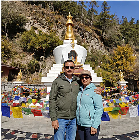A couple beside a white chorten hung with prayer flags on an Ayansh Holidays Bhutan tour